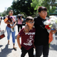 A woman and a childarrive to Robb Elementary school with flowers, the day after a gunman killed 19 children and two teachers at the school in Uvalde, Texas